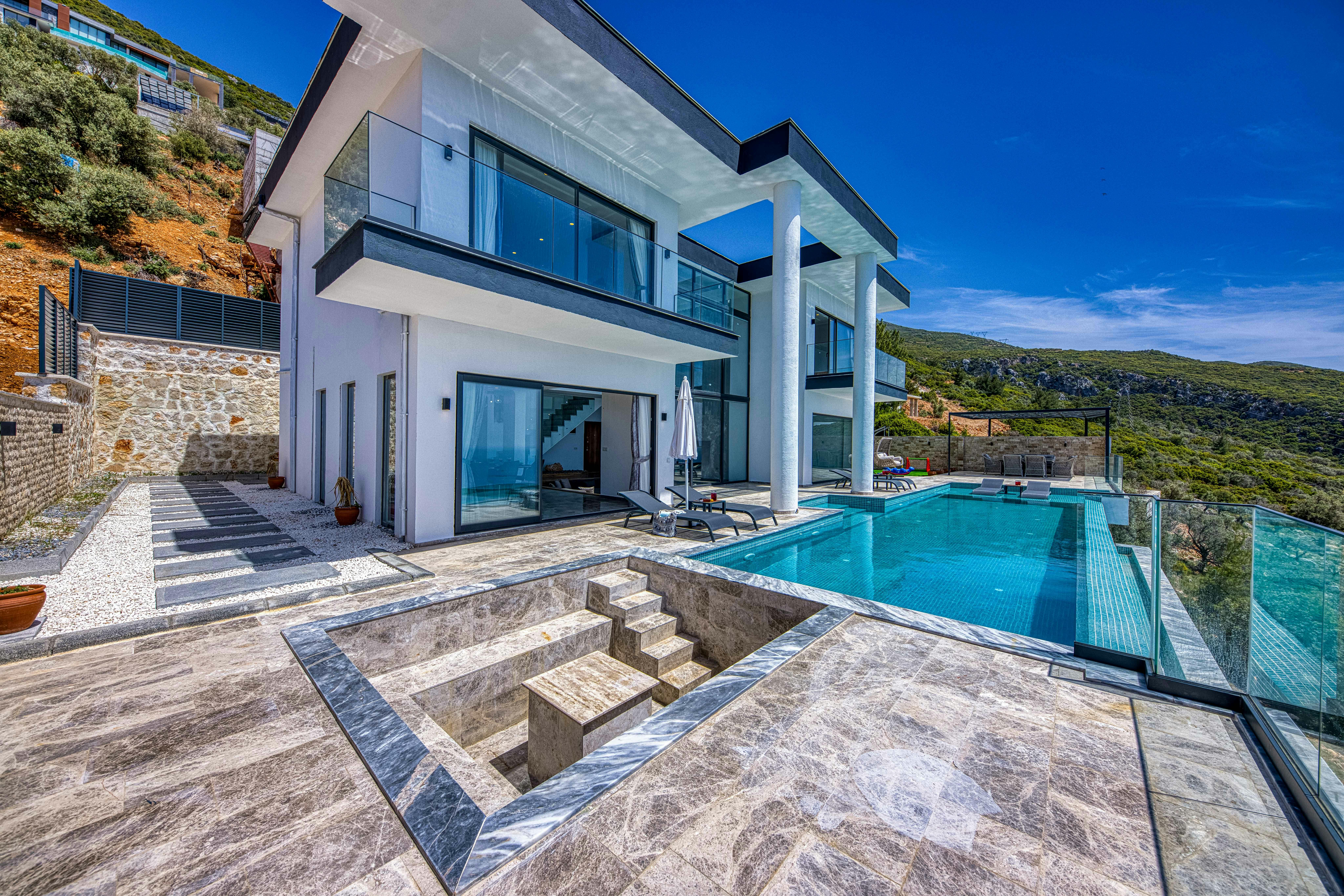 Stunning contemporary villa with glass, stone, and infinity pool; perfect for luxury living.