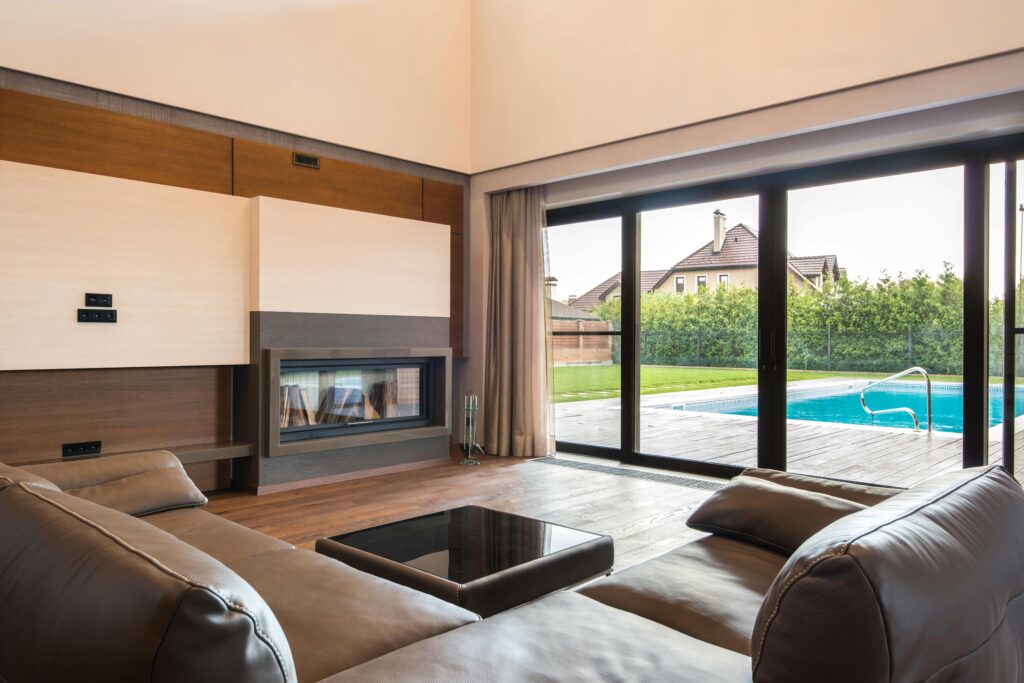 Ventes Spacious modern living room with glass doors opening to a poolside area.