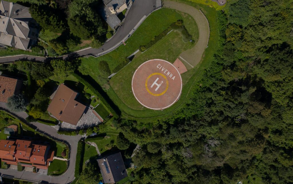 Ventes Drone shot capturing a helipad in Civenna surrounded by greenery and residential houses.