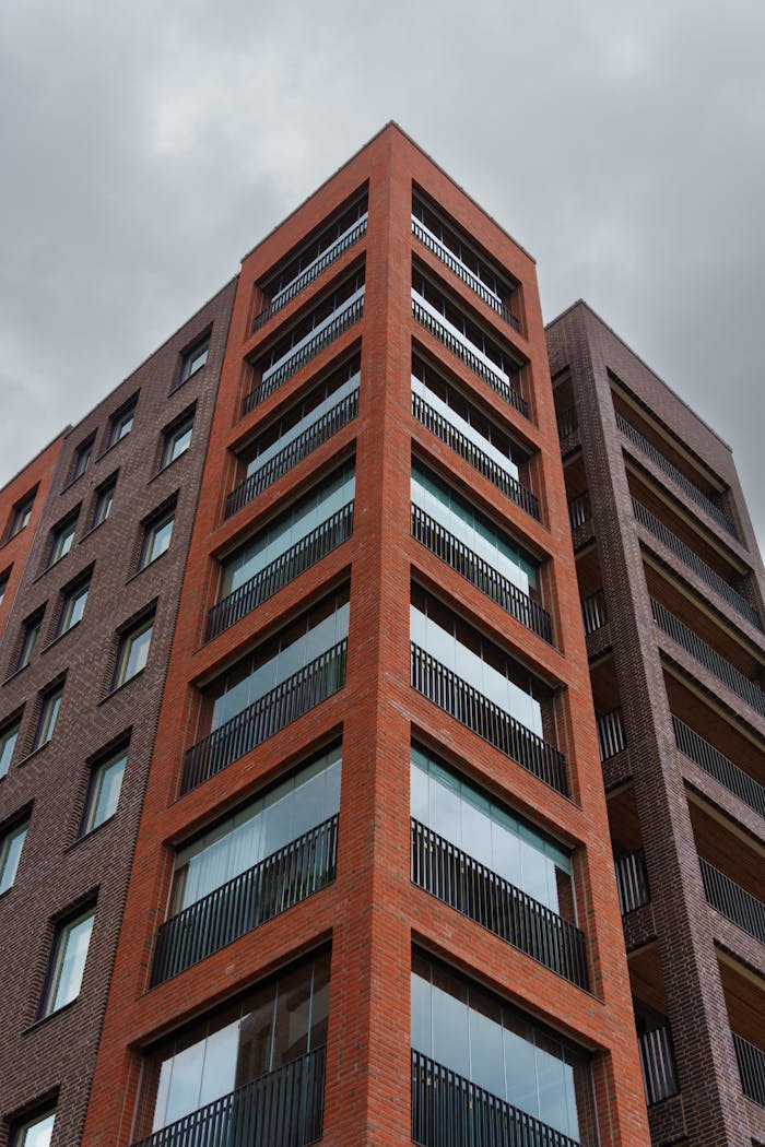 about-us-02 Low angle view of a modern apartment building against a grey sky.