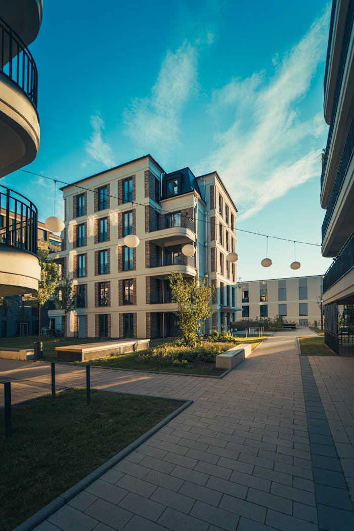 about-us-01 Modern apartment complex under clear blue skies, showcasing contemporary architecture and urban living.