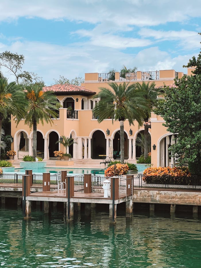 services-04 Elegant Mediterranean style villa with lush palm trees and waterfront view.